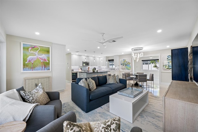 living room with ceiling fan with notable chandelier and beverage cooler