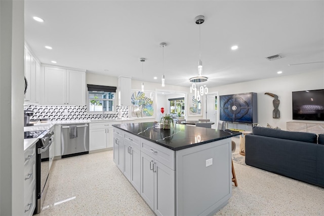 kitchen featuring white cabinetry, stainless steel appliances, tasteful backsplash, decorative light fixtures, and a kitchen island