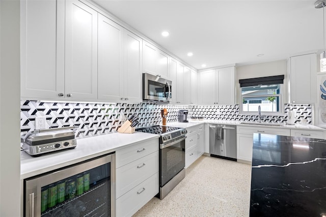 kitchen with pendant lighting, white cabinets, sink, stainless steel appliances, and beverage cooler