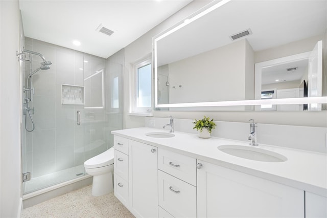 bathroom featuring a shower with door, vanity, and toilet