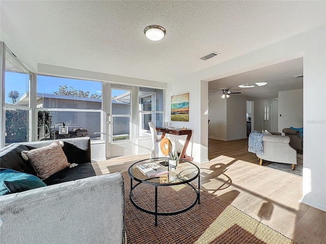 living room featuring hardwood / wood-style flooring, ceiling fan, and a textured ceiling