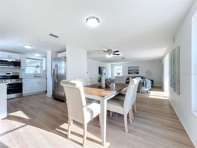 dining space featuring ceiling fan, light wood-type flooring, and sink