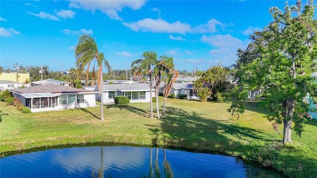 rear view of property with a sunroom, a water view, and a lawn