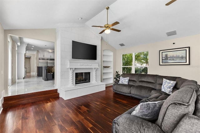 living room with visible vents, a ceiling fan, wood-type flooring, vaulted ceiling, and a fireplace