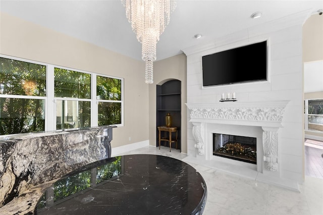 living room with arched walkways, marble finish floor, a notable chandelier, a large fireplace, and baseboards