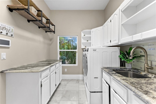 washroom with marble finish floor, cabinet space, a sink, independent washer and dryer, and baseboards