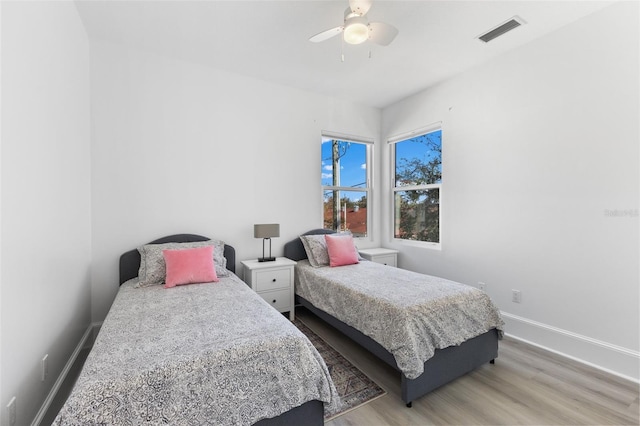 bedroom featuring visible vents, ceiling fan, baseboards, and wood finished floors