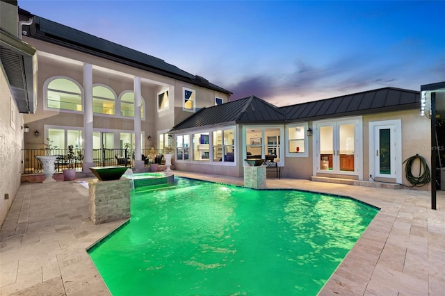 view of swimming pool featuring a pool with connected hot tub, a patio, and french doors