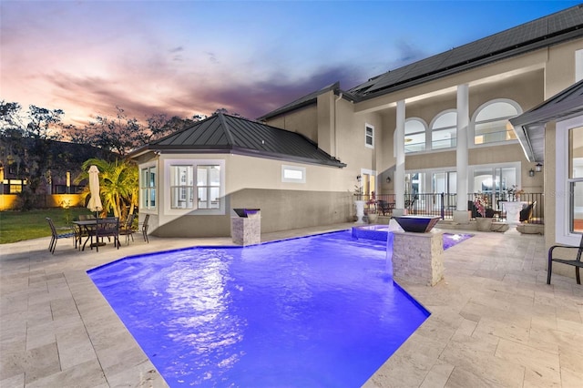 pool at dusk featuring outdoor dining space, a fenced in pool, and a patio