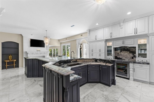 kitchen featuring marble finish floor, white cabinets, a sink, and beverage cooler