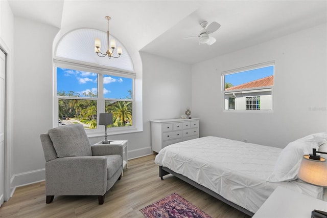 bedroom with baseboards, light wood finished floors, and ceiling fan with notable chandelier