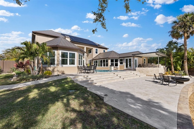 rear view of house featuring a standing seam roof, metal roof, and a patio