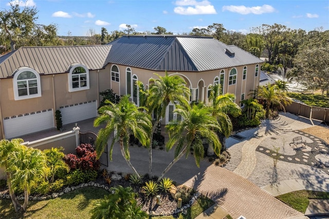 view of front of home with metal roof, a standing seam roof, a fenced front yard, and stucco siding