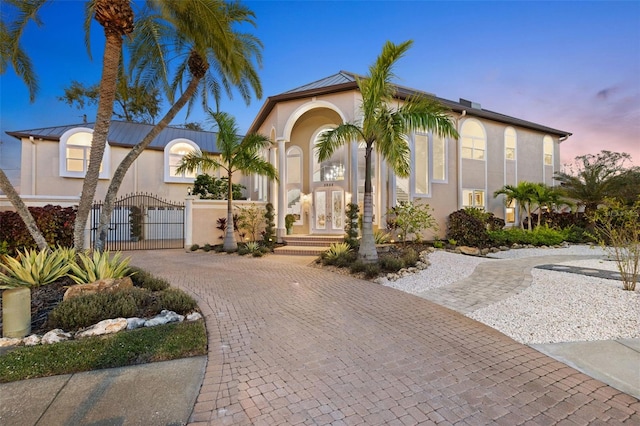 view of front of house with a gate, french doors, and stucco siding