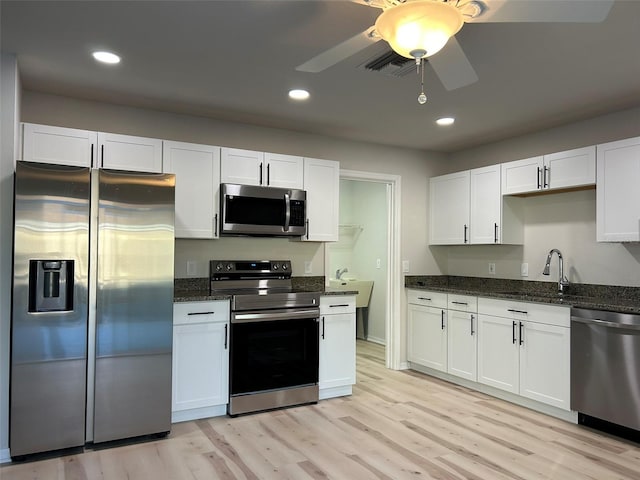 kitchen with white cabinets, appliances with stainless steel finishes, and light wood-type flooring