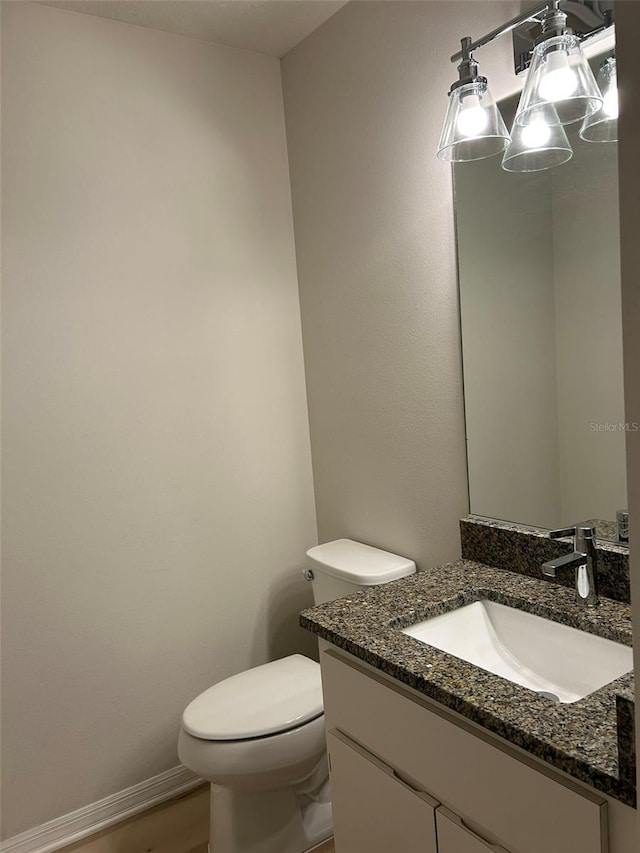 bathroom with toilet, vanity, and baseboards