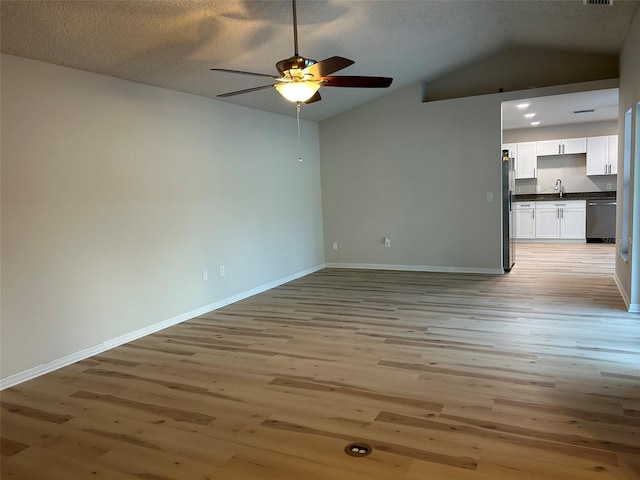 unfurnished room with baseboards, light wood-style flooring, a ceiling fan, and vaulted ceiling