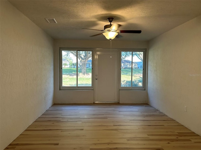 entryway with a textured wall, visible vents, and light wood finished floors