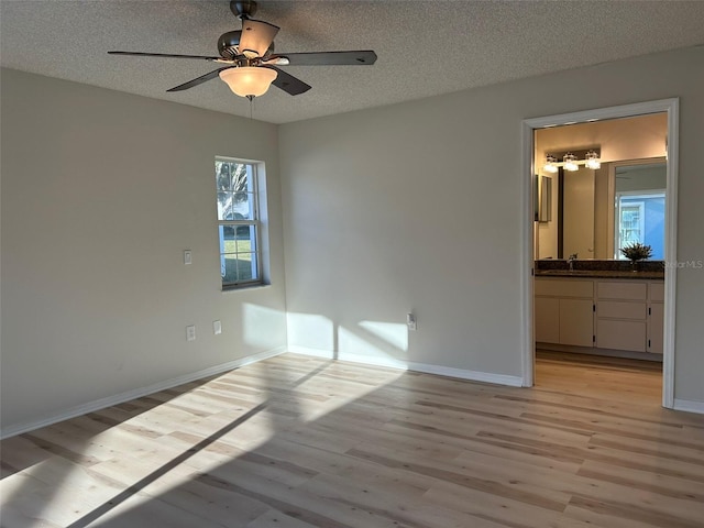 unfurnished bedroom with baseboards, a textured ceiling, light wood-style flooring, and a ceiling fan