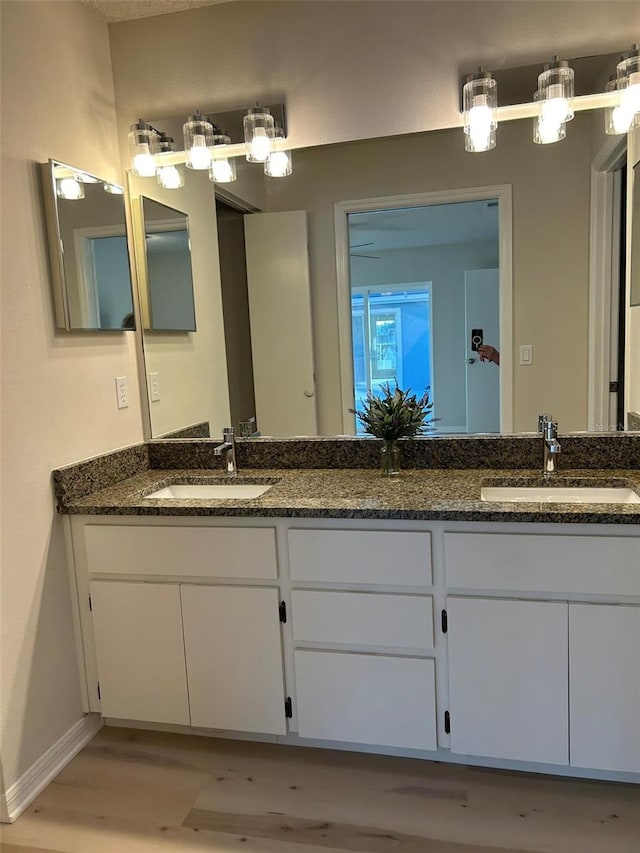 bathroom with double vanity, baseboards, and a sink