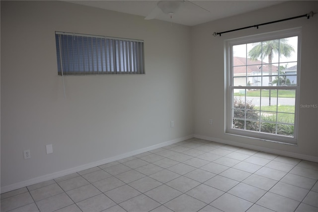 unfurnished room featuring light tile patterned flooring, a ceiling fan, and baseboards