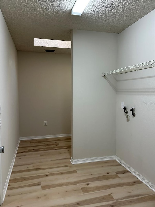 laundry room featuring visible vents, a textured ceiling, light wood finished floors, baseboards, and laundry area