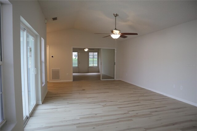 empty room with visible vents, lofted ceiling, baseboards, and light wood-style flooring