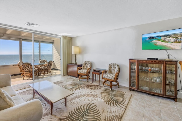 tiled living room with a textured ceiling and a water view