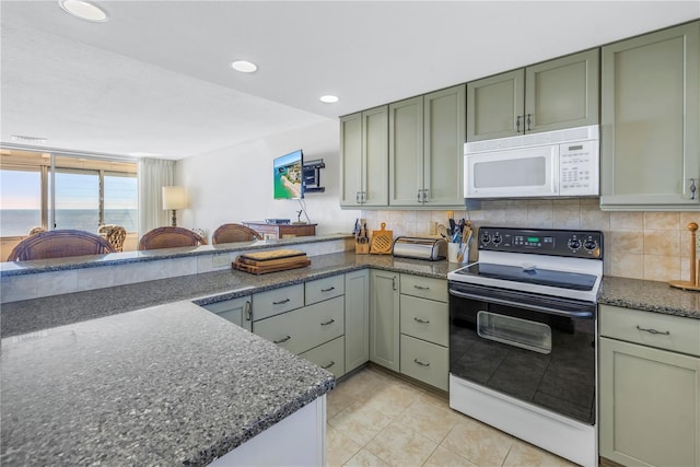 kitchen featuring backsplash, kitchen peninsula, white appliances, and green cabinetry