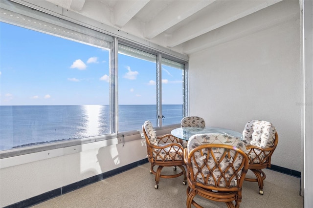 sunroom with beam ceiling and a water view