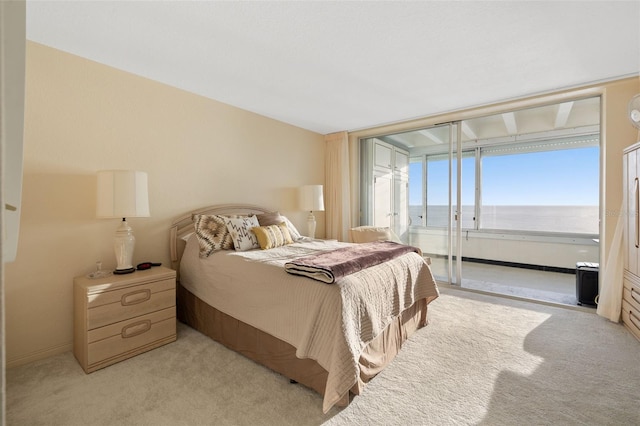 bedroom with light carpet, access to outside, and a water view