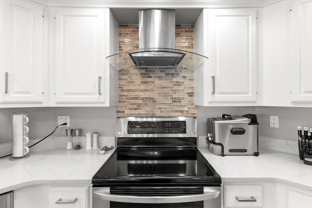 kitchen with tasteful backsplash, white cabinets, stainless steel range with electric cooktop, and wall chimney range hood