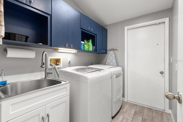 laundry area with cabinets, light wood-type flooring, washing machine and dryer, and sink