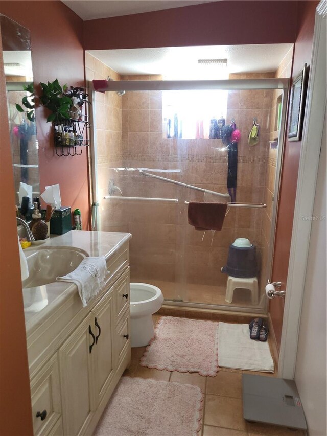 bathroom with tile patterned flooring, vanity, toilet, and an enclosed shower