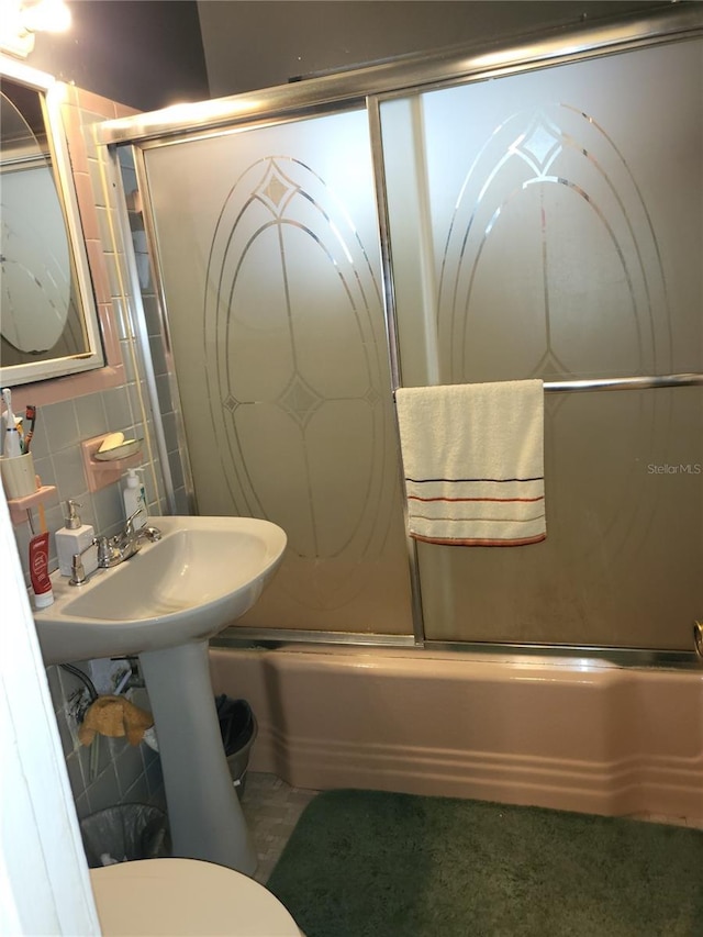 bathroom featuring backsplash, toilet, and combined bath / shower with glass door