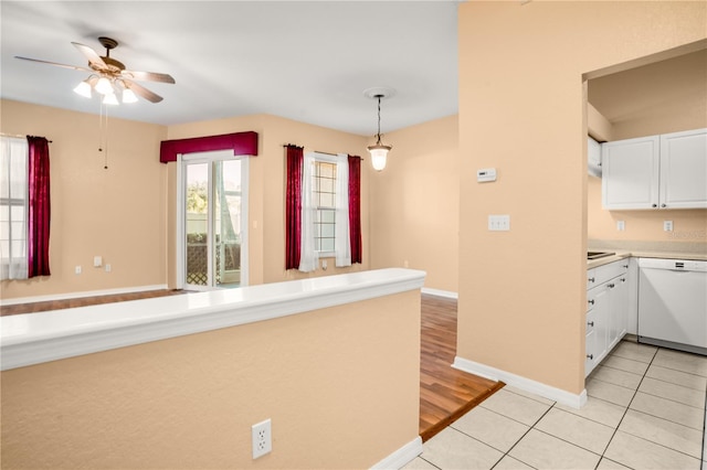 kitchen featuring pendant lighting, white dishwasher, ceiling fan, light tile patterned floors, and white cabinetry