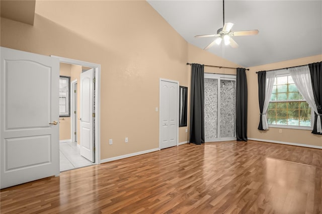 unfurnished bedroom with ceiling fan, high vaulted ceiling, and light wood-type flooring