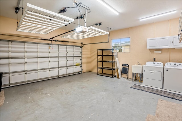 garage featuring washer and clothes dryer, a garage door opener, and sink