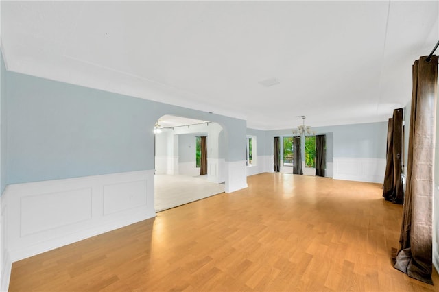 empty room with a notable chandelier and light hardwood / wood-style flooring