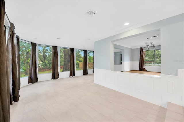 unfurnished living room with a wall of windows, crown molding, and an inviting chandelier