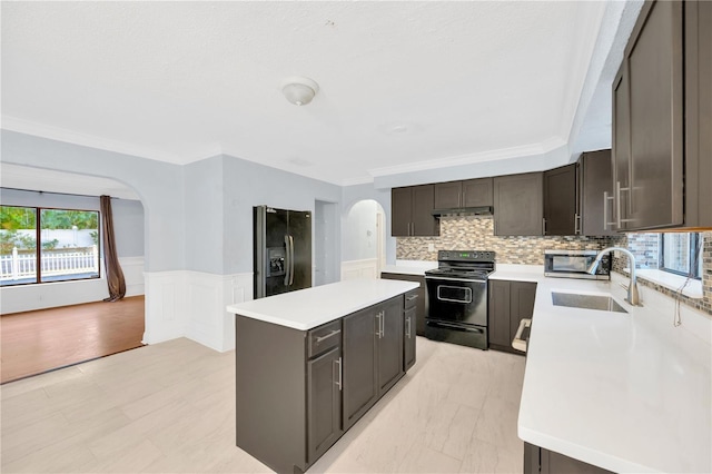 kitchen featuring black range with electric stovetop, a center island, sink, stainless steel fridge, and crown molding