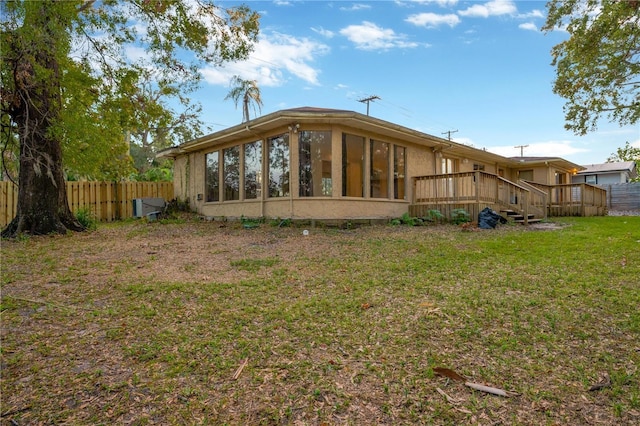 rear view of house featuring a sunroom, a deck, and a yard