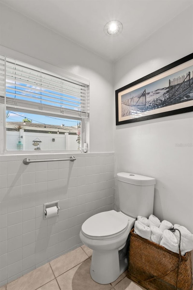 bathroom featuring toilet, tile patterned floors, and tile walls