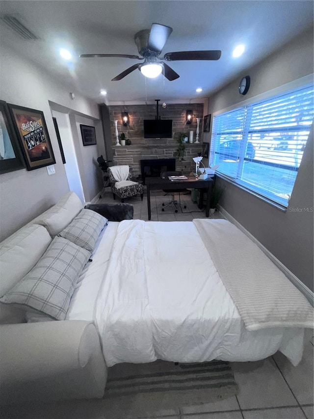 tiled bedroom with ceiling fan and a fireplace