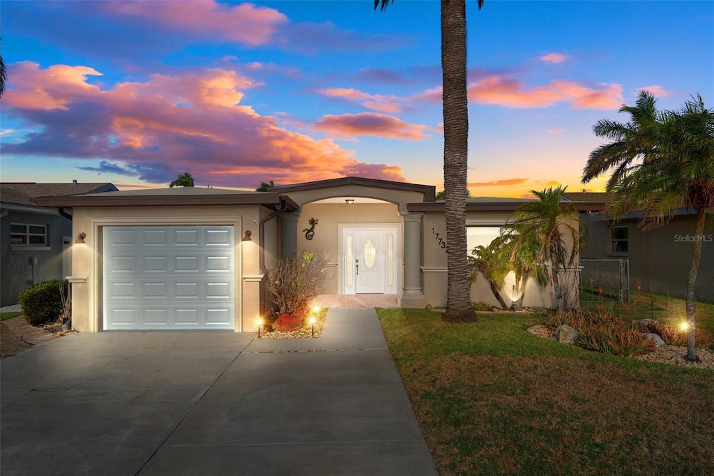 ranch-style house with a garage and a lawn