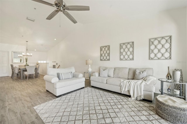 living room featuring ceiling fan with notable chandelier, high vaulted ceiling, and light hardwood / wood-style flooring