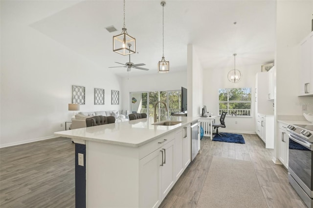 kitchen with white cabinets, sink, hardwood / wood-style flooring, an island with sink, and appliances with stainless steel finishes