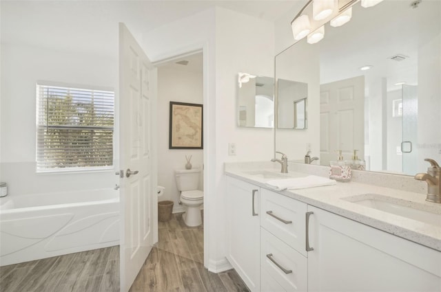 bathroom with vanity, hardwood / wood-style flooring, toilet, and a tub