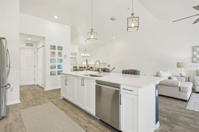 kitchen with appliances with stainless steel finishes, a kitchen island with sink, sink, decorative light fixtures, and white cabinets