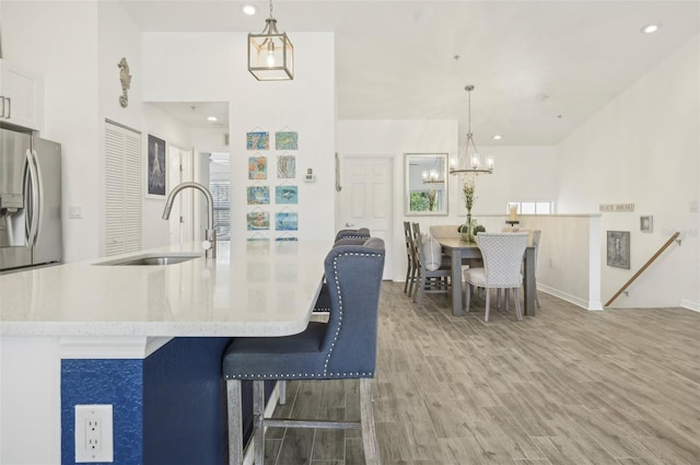 kitchen featuring decorative light fixtures, stainless steel fridge, wood-type flooring, and sink